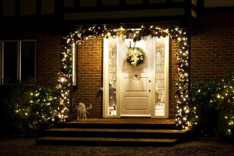 Groene kerstkrans met rode bessen voor buiten, hangende aan voordeur als feestelijke versiering