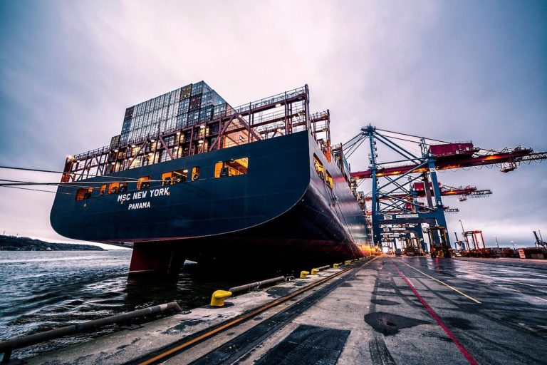 Moderne breakbulk terminal met grote kraan, containers en aangemeerde schepen in de haven