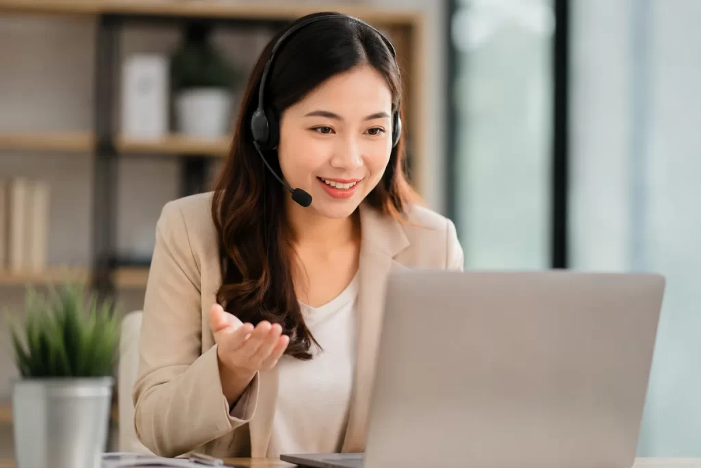 Een vriendelijke ondernemer met headset in een moderne werkruimte tijdens een online gesprek.