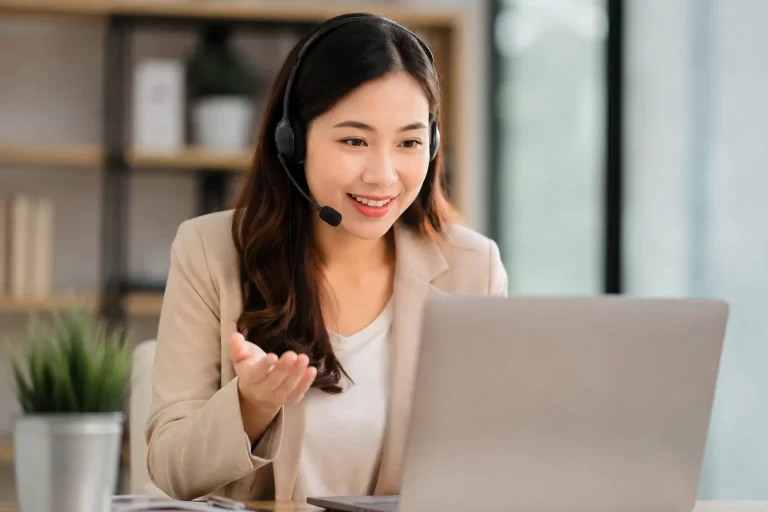 Een vriendelijke ondernemer met headset in een moderne werkruimte tijdens een online gesprek.