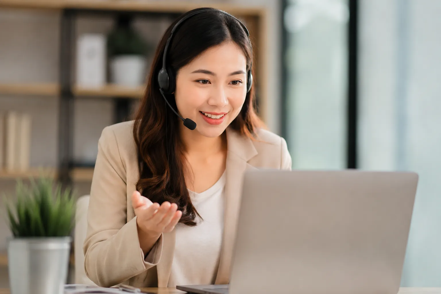 Een vriendelijke ondernemer met headset in een moderne werkruimte tijdens een online gesprek.